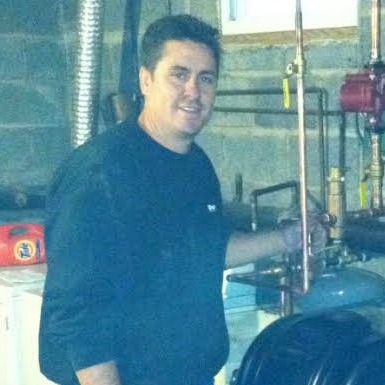 Von Plumbing & Heating owner working alongside heating equipment.